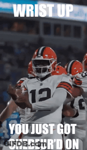 A Football Player With The Number 12 On His Jersey Is Surrounded By His Teammates GIF