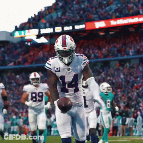 A Football Player With The Number 14 On His Jersey Is Holding A Ball GIF