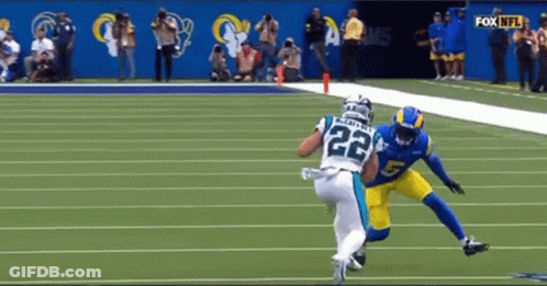 A Football Player With The Number 22 On His Jersey Is Being Tackled By Another Player On The Field . GIF