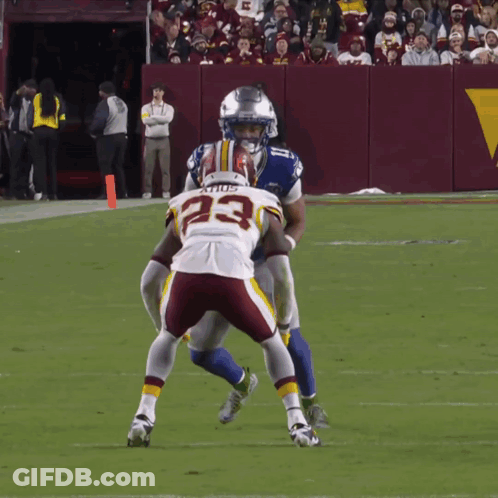 A Football Player With The Number 23 On His Jersey Is Being Tackled By Another Player GIF