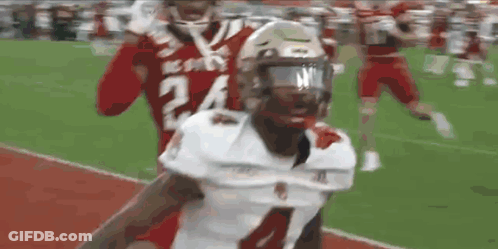 A Football Player With The Number 24 On His Jersey Is Being Tackled By Another Player On A Field . GIF