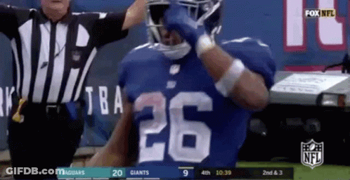 A Football Player With The Number 26 On His Jersey Is Standing In Front Of A Referee . GIF
