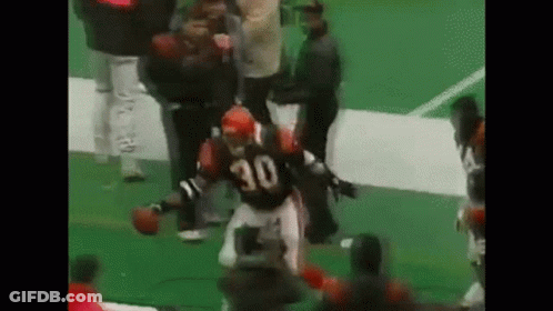 A Football Player With The Number 30 On His Jersey Is Running On A Field With A Football . GIF