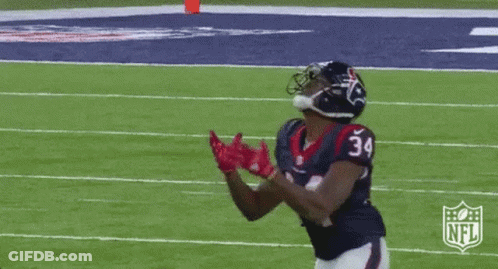 A Football Player With The Number 34 On His Jersey Is Catching A Pass On A Field . GIF