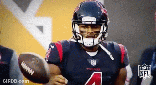 A Football Player With The Number 4 On His Jersey Is Holding A Football In His Hand . GIF