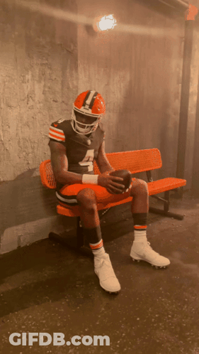 A Football Player With The Number 4 On His Jersey Sits On An Orange Bench GIF