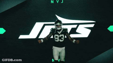 A Football Player With The Number 83 On His Jersey Stands In Front Of A Jets Logo GIF