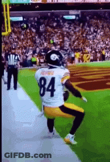 A Football Player With The Number 84 On His Jersey Is Squatting On The Field GIF