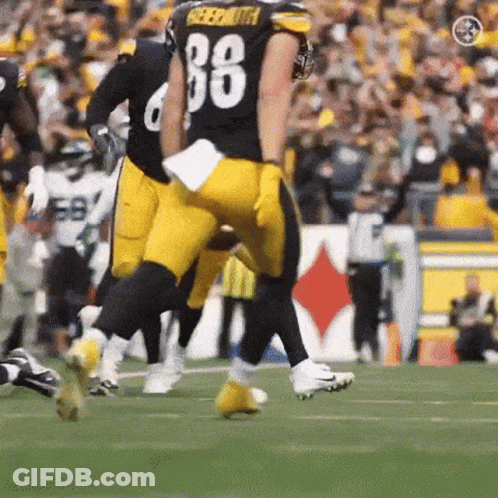 A Football Player With The Number 88 On His Jersey Is Running On A Field . GIF