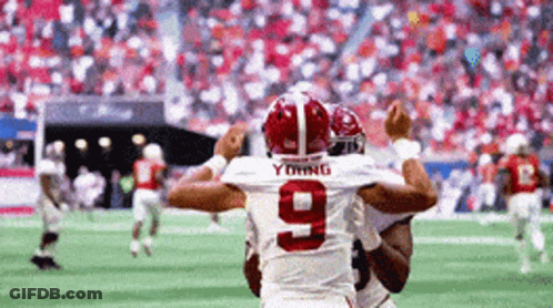 A Football Player With The Number 9 On His Jersey Is Being Hugged By Another Player On The Field . GIF