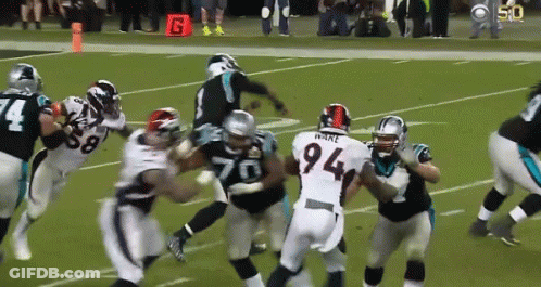 A Football Player With The Number 94 On His Jersey Is Surrounded By Other Players GIF