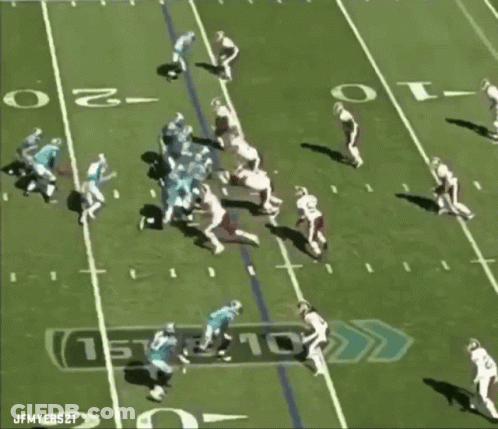 A Football Player With The Number 98 On His Jersey Is Being Tackled GIF