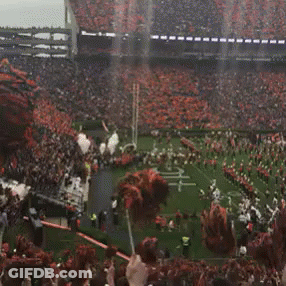 A Football Stadium With A Marching Band And Cheerleaders On The Field GIF