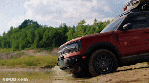 A Ford Bronco Is Driving Through A Muddy Area GIF