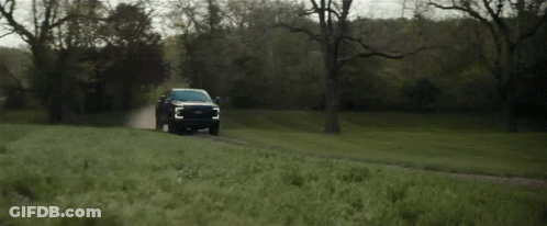 A Ford Truck Is Driving Down A Dirt Road GIF