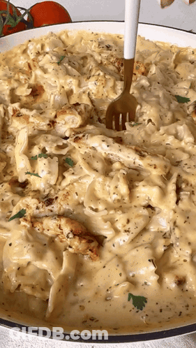 A Fork Is In A Bowl Of Pasta With Chicken And Cheese GIF