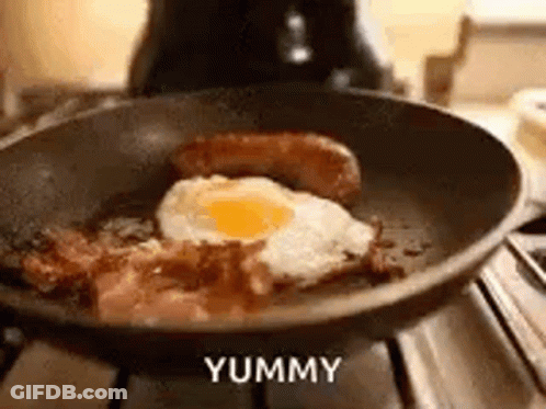 A Frying Pan Filled With Bacon , Eggs , And Sausage On A Stove . GIF