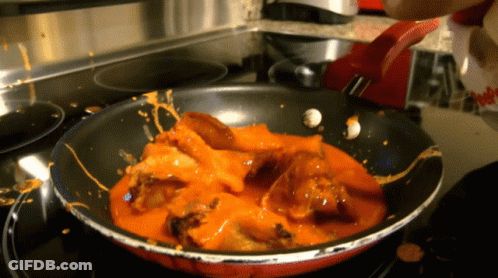 A Frying Pan Filled With Chicken And Sauce Is On A Stove Top GIF
