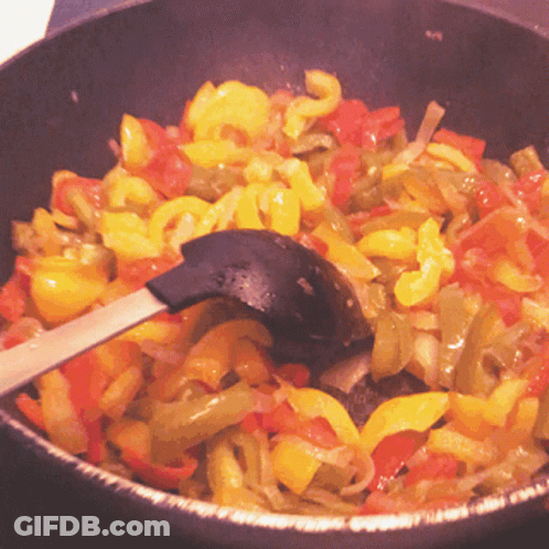A Frying Pan Filled With Vegetables And A Spoon GIF