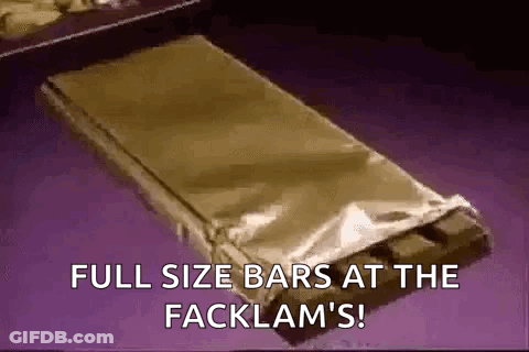 A Full Size Bar Of Chocolate Is Wrapped In Foil And Sitting On A Table . GIF