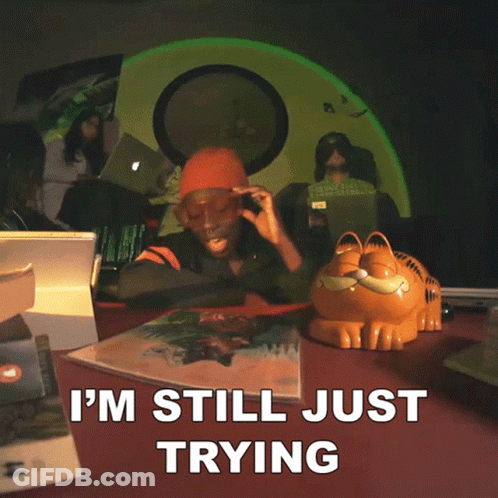A Garfield Statue Sits On A Table Next To A Woman Wearing Sunglasses And A Sign That Says " To Make You Stay " GIF