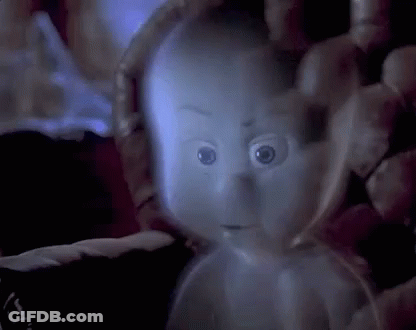 A Ghost Is Being Held In Someone 'S Hand In A Dark Room And Looking At The Camera . GIF