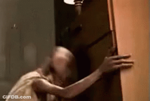 A Ghost Is Standing In A Doorway Holding A Door . GIF