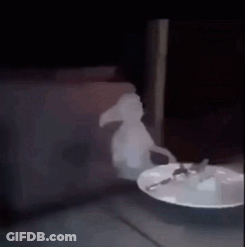 A Ghost Is Standing Next To A Plate Of Food With A Spoon On It . GIF