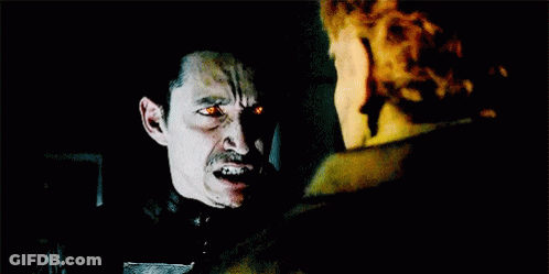 A Ghost Rider With Flames Coming Out Of His Face Is Standing Next To A Skeleton . GIF