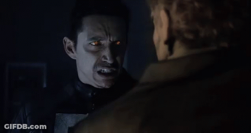 A Ghost Rider With Flames Coming Out Of His Head Is Standing Next To A Man . GIF
