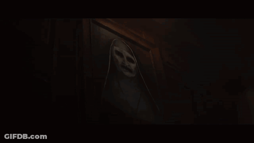 A Ghost With A Scary Face Is Behind A Door In A Dark Room GIF