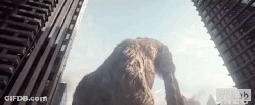 A Giant Elephant Is Standing In The Middle Of A City Looking Up At A Skyscraper .. GIF