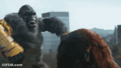 A Giant Gorilla Is Standing Next To A Woman In A City . GIF