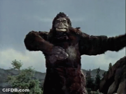 A Giant Gorilla Is Standing On Top Of A Rocky Hill . GIF