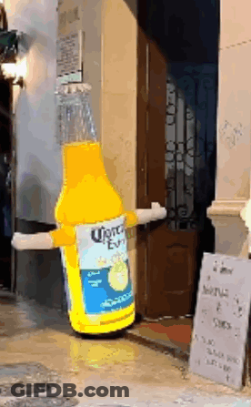 A Giant Inflatable Bottle Of Corona Beer Is Standing In Front Of A Building GIF