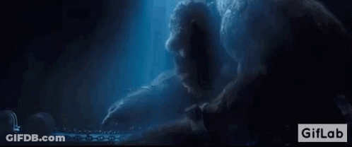 A Giant Monster Is Sitting On A Table In The Dark . GIF