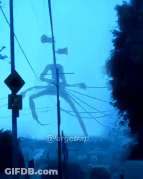A Giant Monster With A Siren Head Is Standing In The Middle Of A Street GIF
