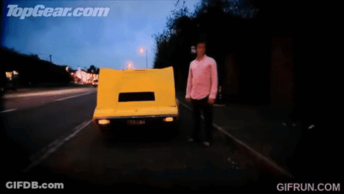 A GIF From Topgear.com Shows A Yellow Car Driving Down The Road GIF