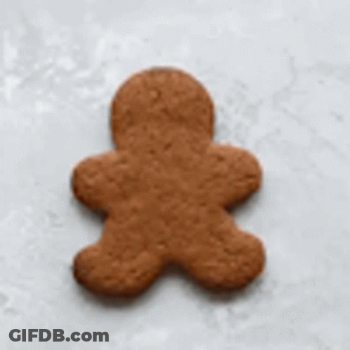 A Gingerbread Man Is Being Decorated With White Frosting . GIF