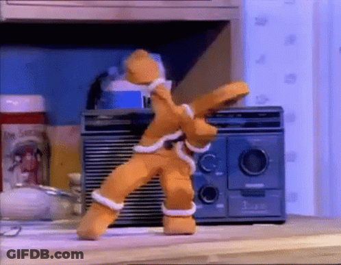 A Gingerbread Man Is Dancing In Front Of A Radio On A Table . GIF