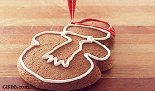 A Gingerbread Man Is Decorated With White Frosting And A Red Ribbon GIF