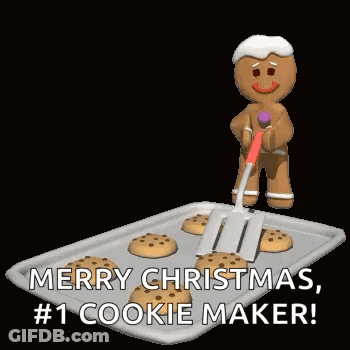 A Gingerbread Man Is Holding A Spatula Over A Tray Of Cookies And Wishing Merry Christmas . GIF