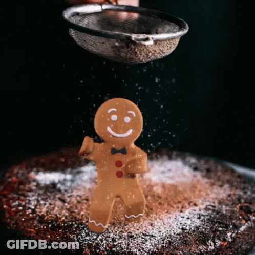 A Gingerbread Man With A Bow Tie Is Being Sprinkled With Powdered Sugar GIF