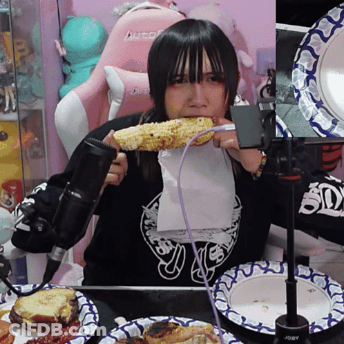A Girl Eating Corn On The Cob With A Purple Cord GIF