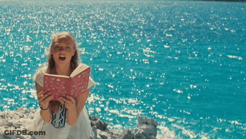 A Girl Holding A Book That Says ' I Love You ' On It GIF