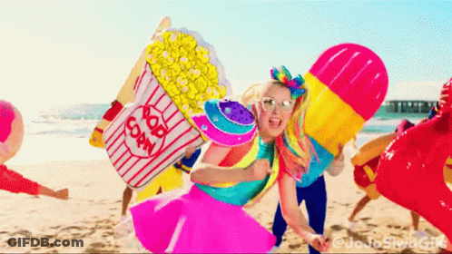 A Girl Holding A Popcorn Bucket On A Beach GIF