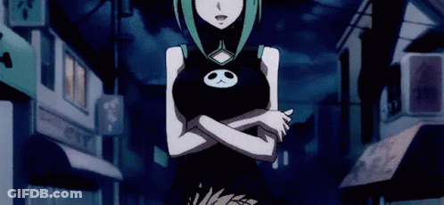 A Girl In A Black Dress With A Skull On Her Chest Is Standing In A Dark Street . GIF