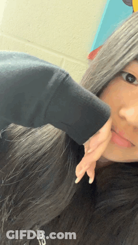 A Girl In A Black Sweatshirt Is Taking A Selfie GIF
