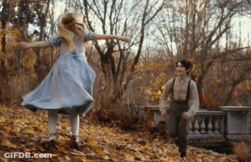 A Girl In A Blue Dress And A Boy In Suspenders Are Running Through A Forest . GIF