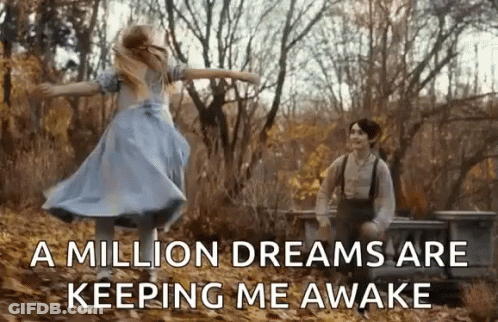 A Girl In A Blue Dress Is Dancing In The Woods Next To A Man . GIF